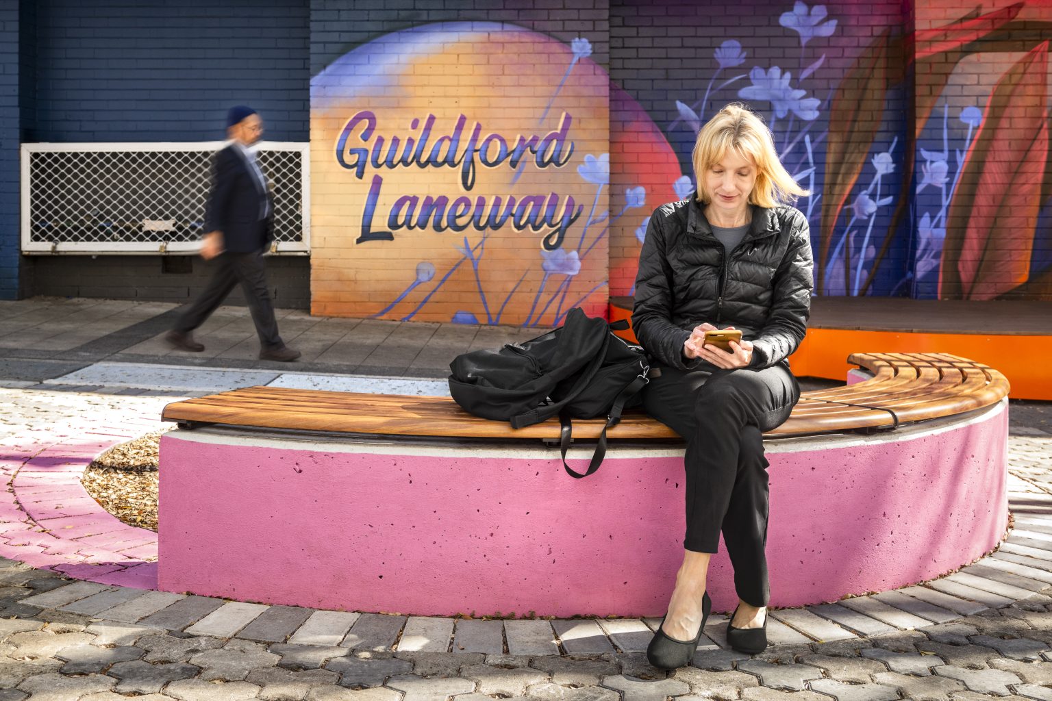Linea Curved Bench (LIB6-C) plinth-fixed, aluminium woodgrain Spotted Gum battens, Textura Monument frame.
