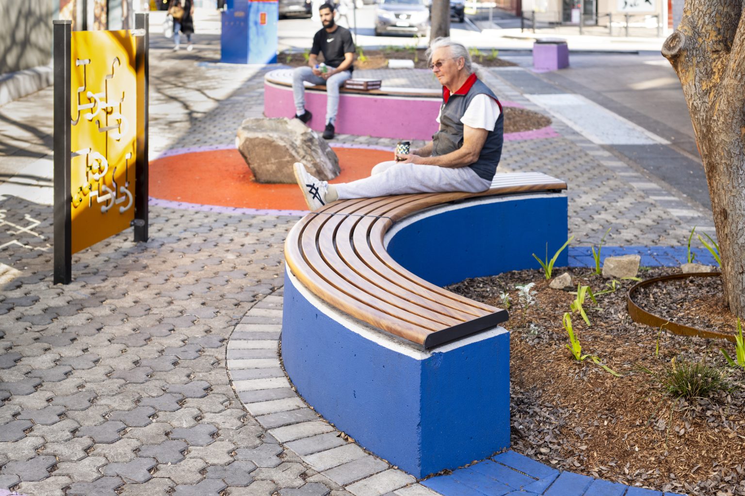 Linea Curved Bench (LIB6-C) plinth-fixed, aluminium woodgrain Spotted Gum battens, Textura Monument frame.