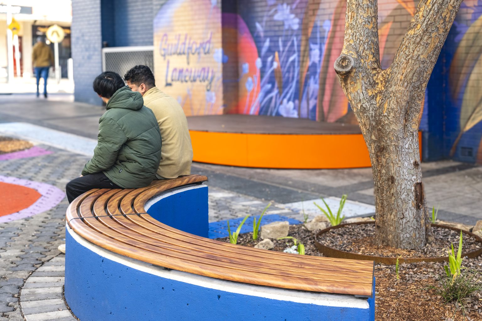 Linea Curved Bench (LIB6-C) plinth-fixed, in aluminium woodgrain Spotted Gum battens, Textura Monument frame.