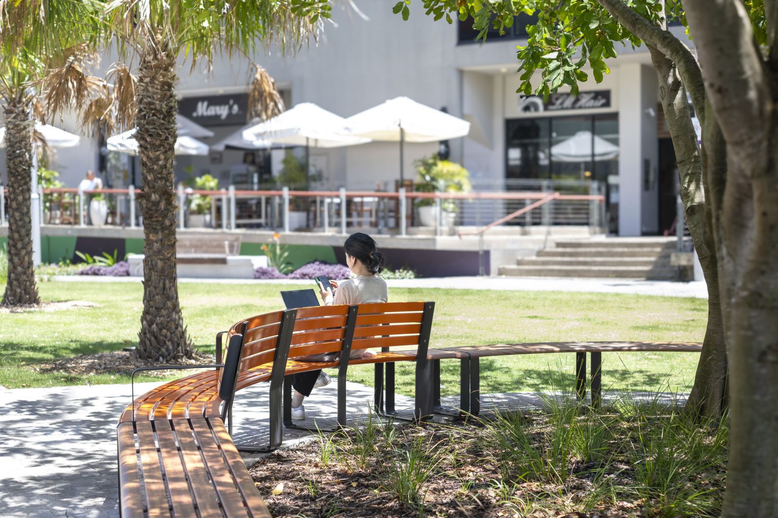 Curved and straight Linea Seats and Benches with frames in Textura Monument, battens in Bistro Orange and aluminium woodgrain Spotted Gum.