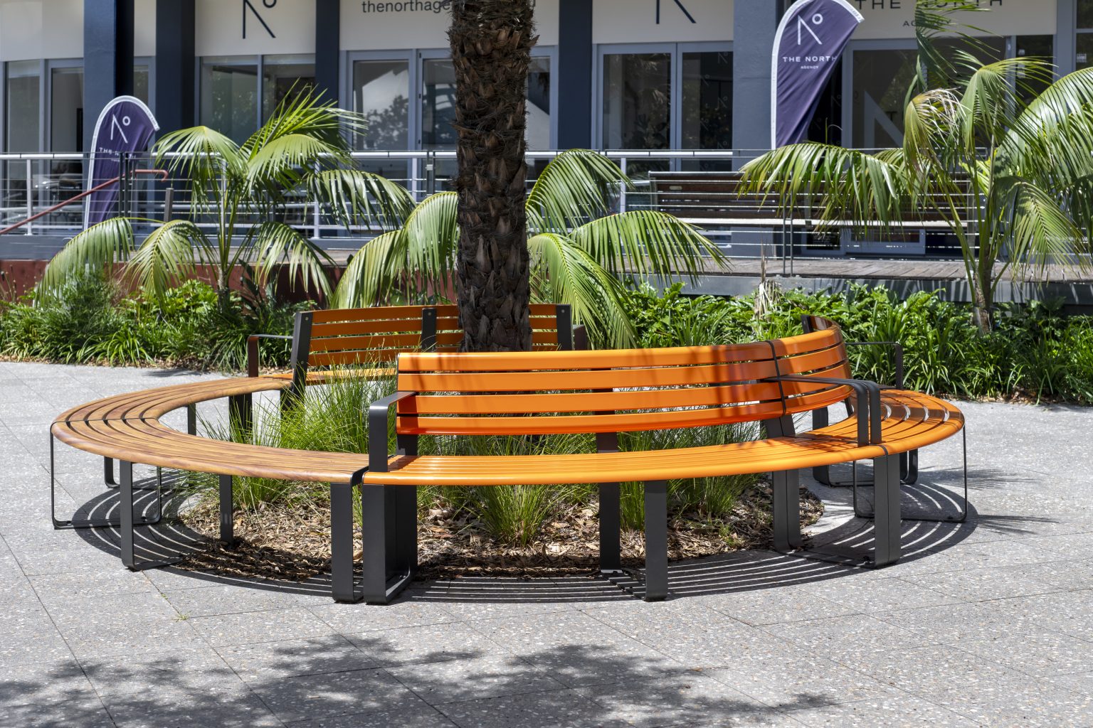 Curved Linea Seats and Benches. Frames in Textura Monument, battens in Bistro Orange and aluminium woodgrain Spotted Gum.
