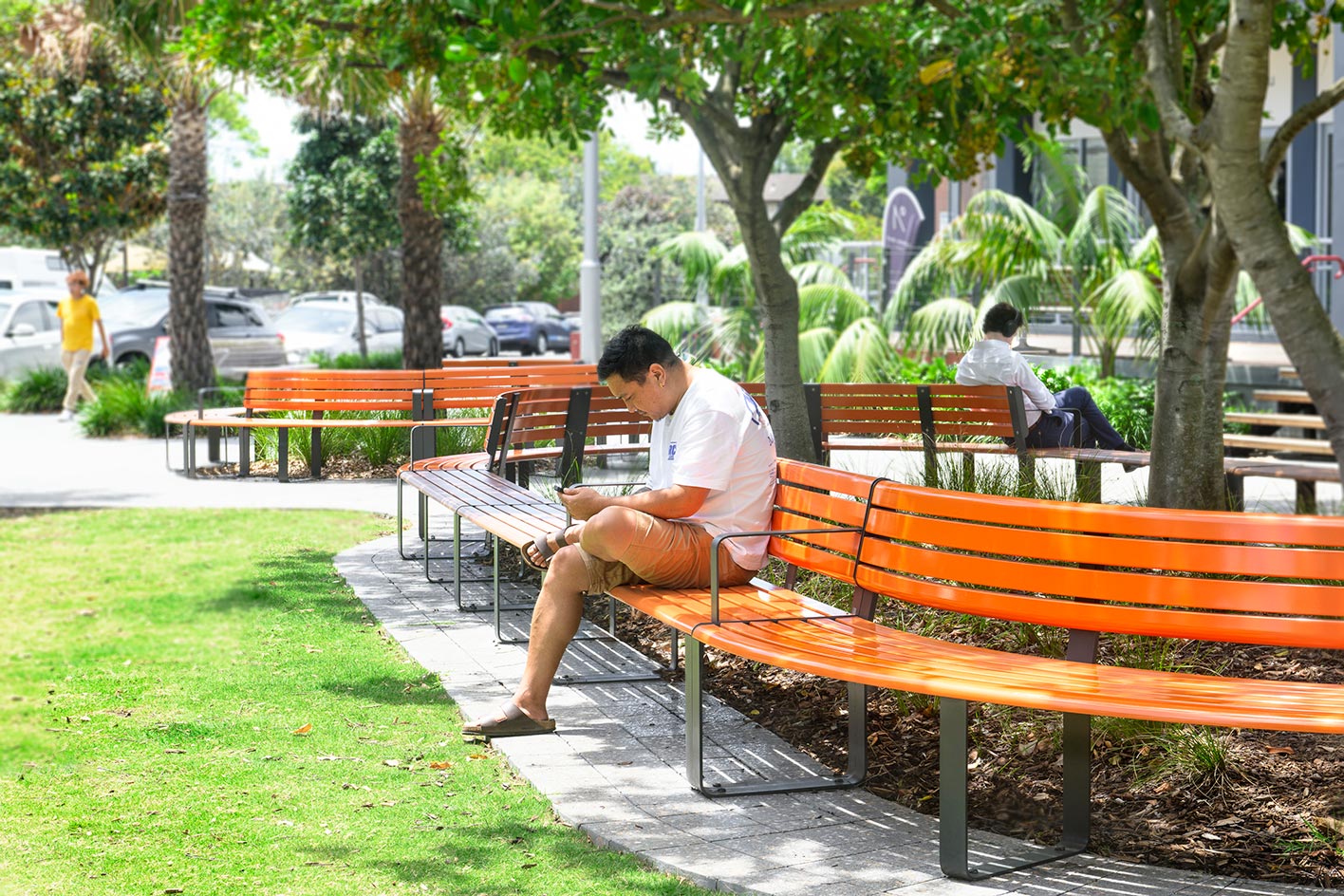 Curved and straight Linea Seats and Benches with frames in Textura Monument, battens in Bistro Orange and aluminium woodgrain Spotted Gum.