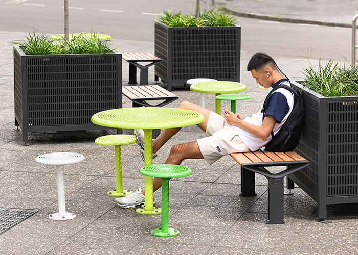 Frame Planters (PT3, Square XL) with Slots perforation in Textura Monument, height-adjustable legs. Aria Bench in aluminium Spotted Gum. Cafe Settings in Lycra Strip Green, Viper Green and Pearl White.