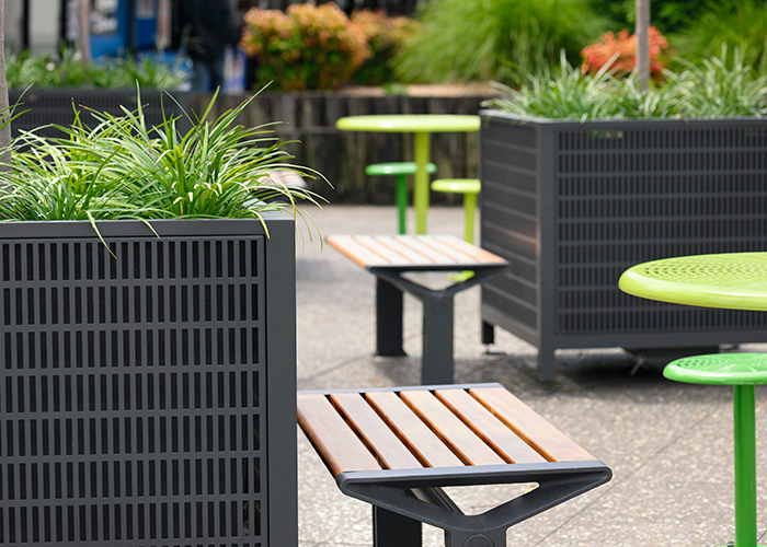Frame Planters (PT3, Square XL) with Slots perforation in Textura Monument, height-adjustable legs. Aria Bench in aluminium Spotted Gum. Cafe Settings in Lycra Strip Green and Viper Green.