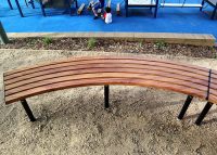 Mall Curved Slim Bench, battens in aluminium woodgrain Spotted Gum, frames in Night Sky.