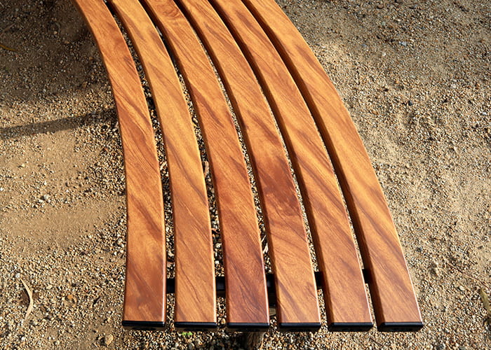 Mall Curved Slim Bench, battens in aluminium woodgrain Spotted Gum, frames in Night Sky.