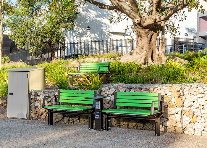 Aria Seat (CMA1, 1200mm) with Viper Green battens, Textura Dark Bronze frame. Custom charging table.
