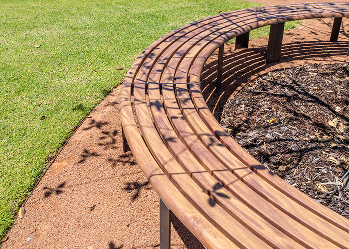 Linea Curved Bench (LIB6-C) with aluminium woodgrain Spotted Gum battens, Textura Dark Bronze frame.