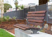 Plinth-mounted Mall DDA Seat with Jarrah battens and frames in tailored colour Metropolis Storm Pearl grey.