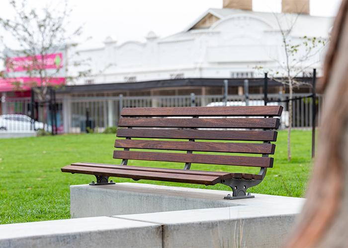 Plinth-mounted Mall DDA Seat with Jarrah battens and frames in tailored colour Metropolis Storm Pearl grey.