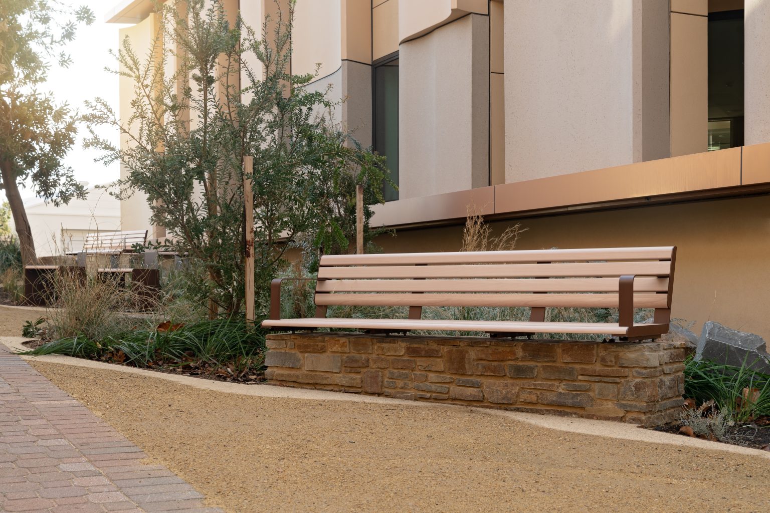 Linea Seat (2100mm, plinth-fixed) with arms, aluminium Curly Birch battens and Textura Core Ten frames.