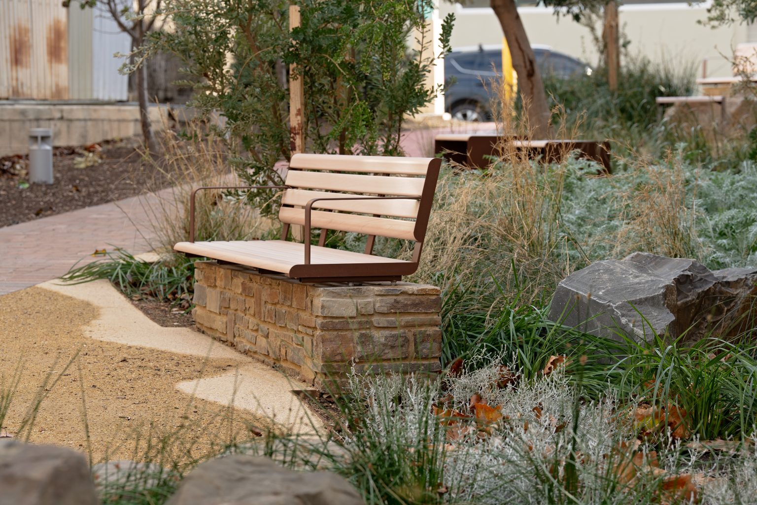 Linea Seat (2100mm, plinth-fixed) with arms, aluminium Curly Birch battens and Textura Core Ten frames.