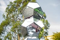 Sculpture reflects street furniture below.